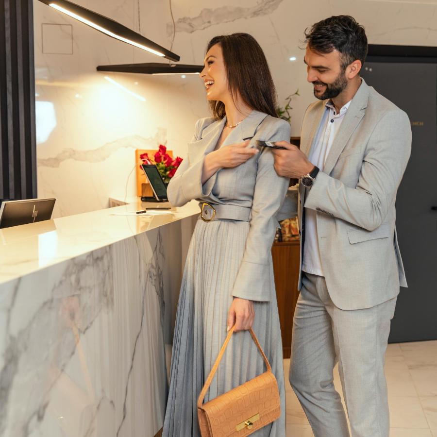 Hotel Pupin ノヴィ・サド エクステリア 写真 A man helping a woman with her coat